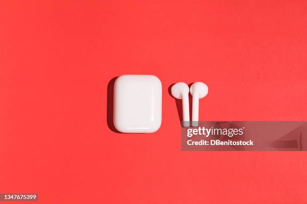 trendy wireless white headphones on red background. - apple white background stock-fotos und bilder