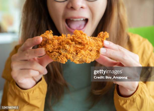 cropped shot of young asian woman open her mouth before eating a piece of crispy fried chicken. - chicken meat fotografías e imágenes de stock