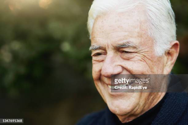 un vieil homme aux cheveux blancs sourit joyeusement à l’extérieur dans un jardin - keratosis photos et images de collection