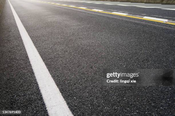 empty road illuminated by sunlight - straßenmarkierung stock-fotos und bilder