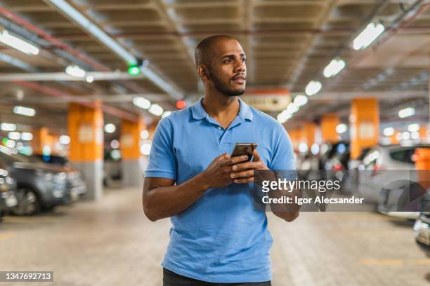 man holding smartphone in parking lot - parking lot stockfoto's en -beelden