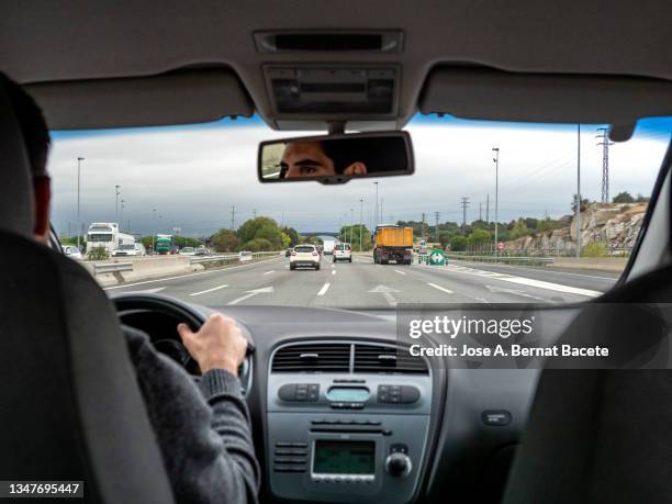 car point of view, young man driving a car on a two-lane highway with a lot of traffic - two lane highway stock-fotos und bilder