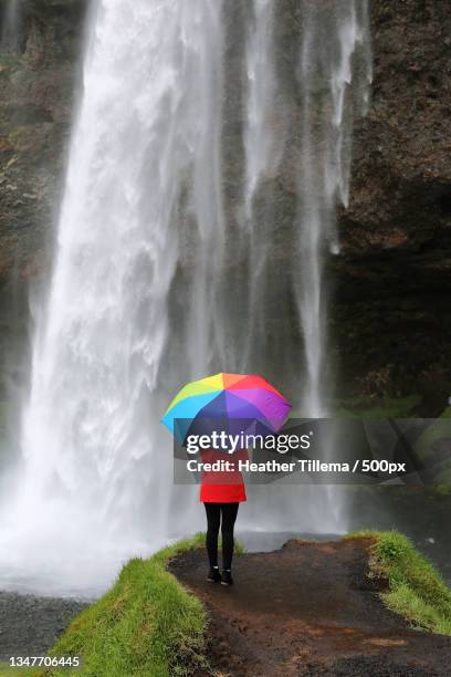 rear view of woman with colorful umbrella standing against waterfall,seljalandsfoss,iceland - 500px plus stockfoto's en -beelden