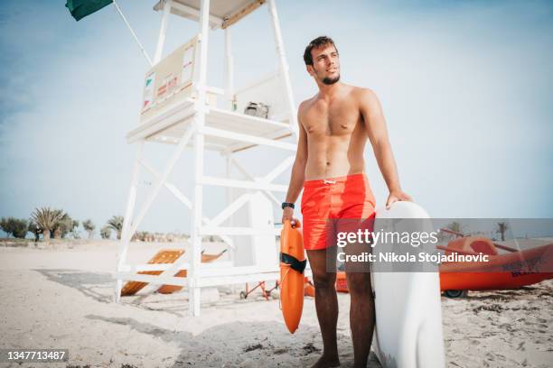 muscular beach lifeguard running along the river bank with life-saving equipment - surf rescue stock pictures, royalty-free photos & images