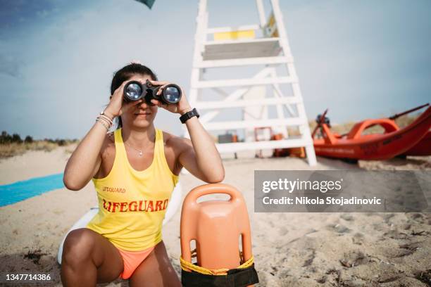rettungsschwimmerin mit rettungsring und fernglas - rettungsschwimmer stock-fotos und bilder