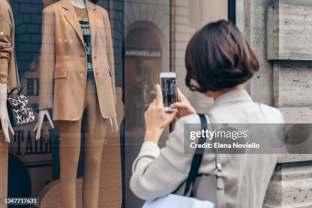 young woman takes pictures on her smartphone of the showcase of the max mara boutique in rome, shopping sales in italy - italian tag foto e immagini stock