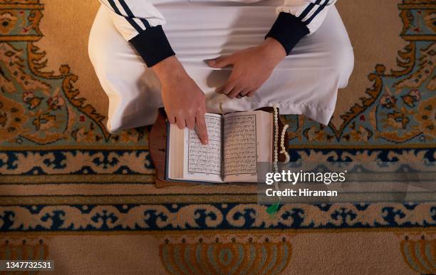 high angle shot of a muslim man reading a quran while praying in a mosque - isfahan imam stock pictures, royalty-free photos & images