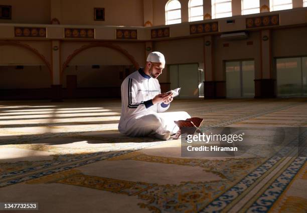 tiro de um jovem muçulmano lendo um alcorão enquanto rezava em uma mesquita - mesquita emam - fotografias e filmes do acervo