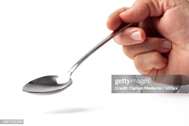 spoon in a hand on white - spoon in hand stock pictures, royalty-free photos & images