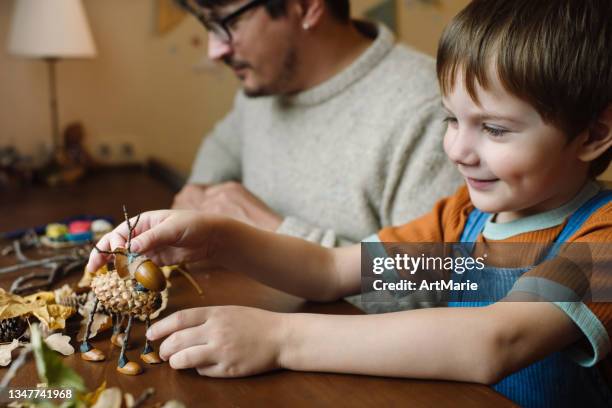 kleiner junge und sein vater basteln im herbst zu hause - bastelarbeit stock-fotos und bilder