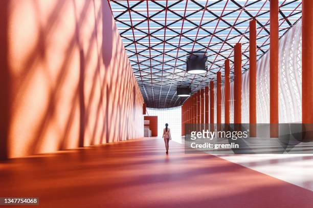 mujer de negocios solitaria caminando en la sala de exposiciones vacía - arquitectura fotografías e imágenes de stock