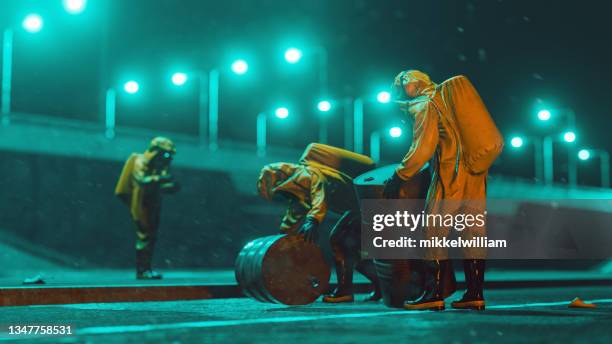 workers with protective workwear move big barrels with chemicals or toxic waste - terrorisme stockfoto's en -beelden