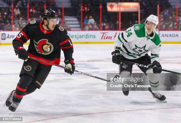 Michael Del Zotto of the Ottawa Senators and Denis Gurianov of the Dallas Stars skate for the puck at Canadian Tire Centre on October 17, 2021 in...