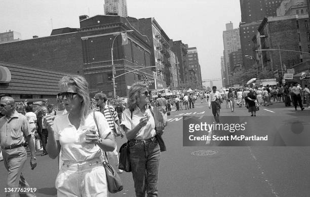Pedestrians, many with food in their hands, walk on 9th Avenue in Hell's Kitchen during the International Food Festival, New York, New York, May 20,...