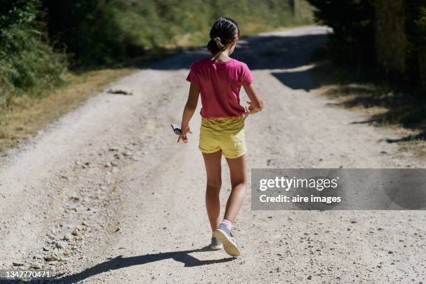 caucasian young girl walking backwards in the middle of a field looking at the sunset - looking backwards stock pictures, royalty-free photos & images