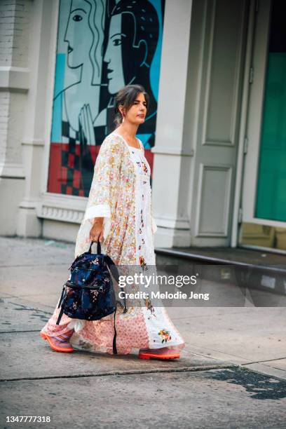 Guest wears a pink and white multi-print and embellished dress and purple floral backpack at the Anna Sui show on September 11, 2021 in New York City.