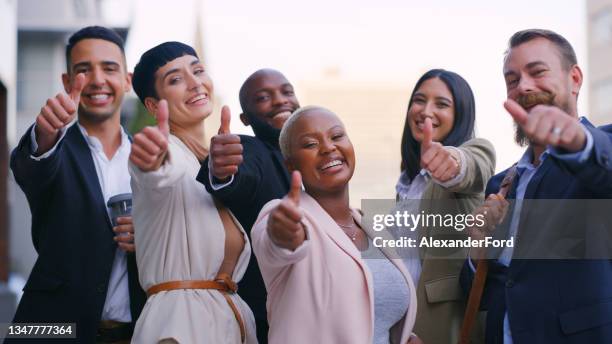 portrait of a group of young businesspeople showing thumbs up against an urban background - black thumbs up white background stock pictures, royalty-free photos & images