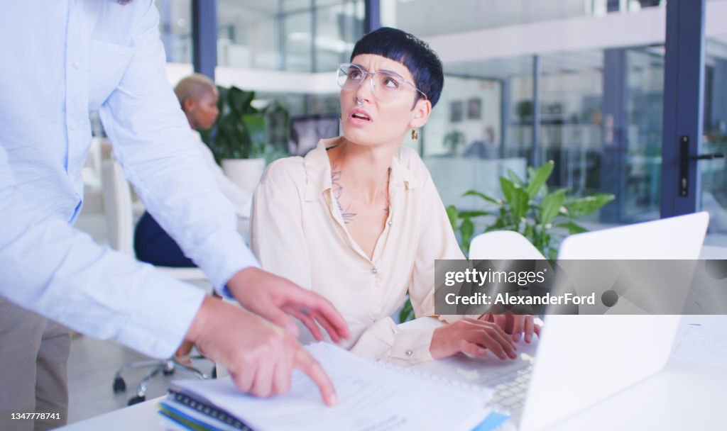Shot of a young businesswoman being handed a pile of paperwork in a modern office