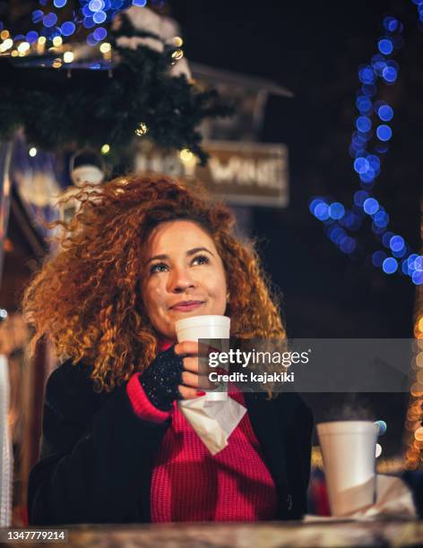 young beautiful woman drinking hot drinks and having fun at christmas market - hot latin nights stock pictures, royalty-free photos & images