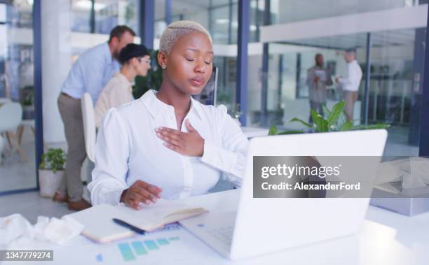 foto de una joven empresaria que se siente mal mientras usa una computadora portátil en una oficina moderna - cardiopatía fotografías e imágenes de stock