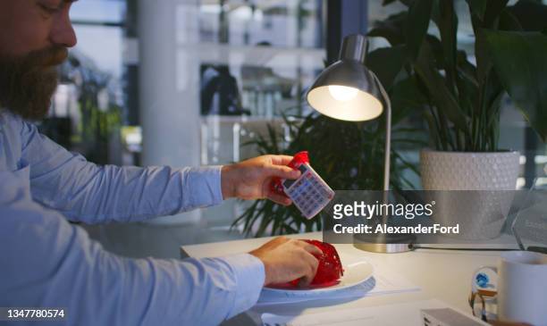 shot of a businessman wiping jelly off of a calculator at his desk in a modern office - april fools day imagens e fotografias de stock