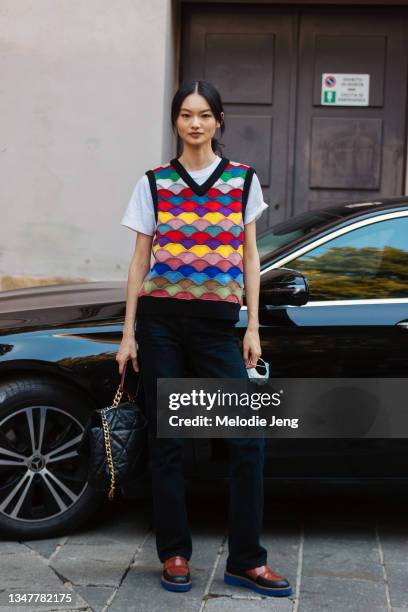 Model He Cong wears a colorful patterned vest, white t-shirt, black jeans, brown loafers, and black Chanel bag after the Alberta Ferretti show during...
