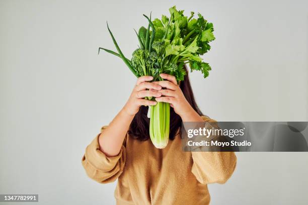 shot of an unrecognizable woman hiding behind a bouquet of vegetables against a white background - celery stock pictures, royalty-free photos & images