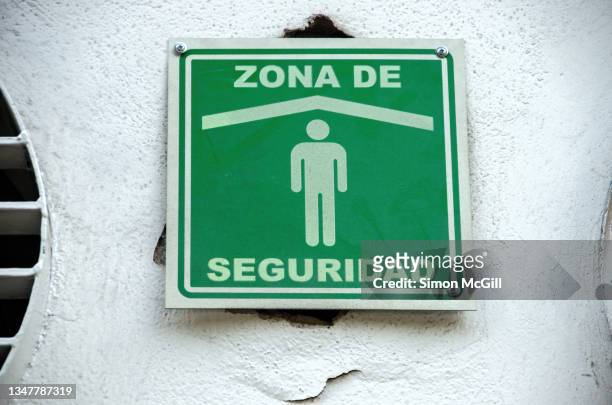 spanish-language sign stating 'zona de seguridad' [safety zone] on an office building exterior - earthquake drill stock pictures, royalty-free photos & images