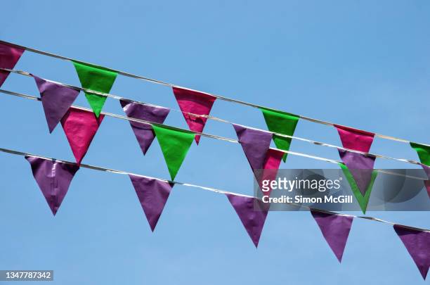 plastic triangular flag bunting hanging across a clear blue sky - mexican bunting stock pictures, royalty-free photos & images