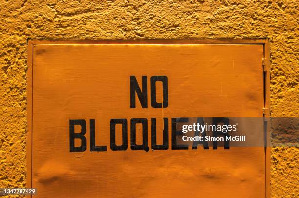 spanish-language sign stating 'no bloquear' [do not block] on the door of a utility room on a building exterior - placa de proibido estacionar imagens e fotografias de stock