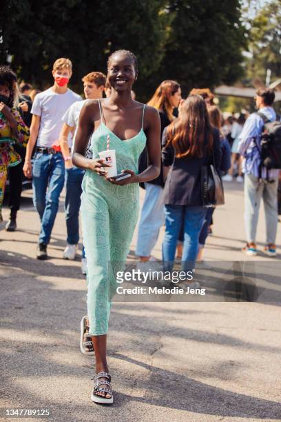 Model Adut Akech wears a green Etro paisley slip dress and white Chanel studded sandals and holds a white Russell x Boss soda cup at the Boss x...