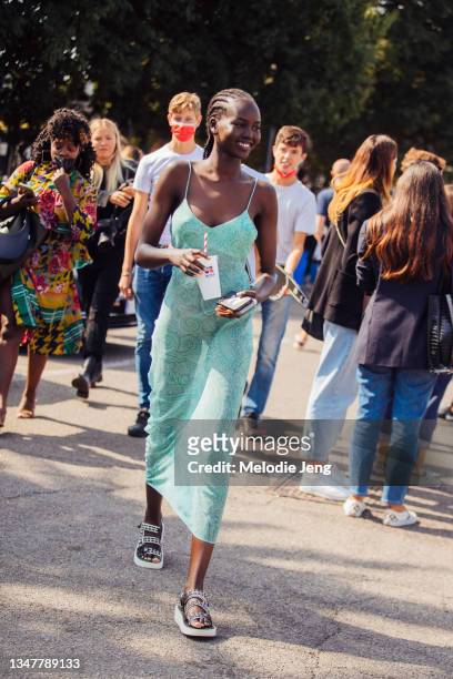 Model Adut Akech wears a green Etro paisley slip dress and white Chanel studded sandals and holds a white Russell x Boss soda cup at the Boss x...