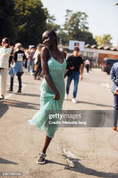 Model Adut Akech wears a green Etro paisley slip dress and white Chanel sandals at the Boss x Russell Athletic show during the Milan Fashion Week -...