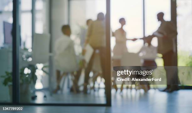 aufnahme von geschäftsleuten, die nach der ankunft bei einem meeting in einem modernen büro die hand schütteln - dark background light stock-fotos und bilder