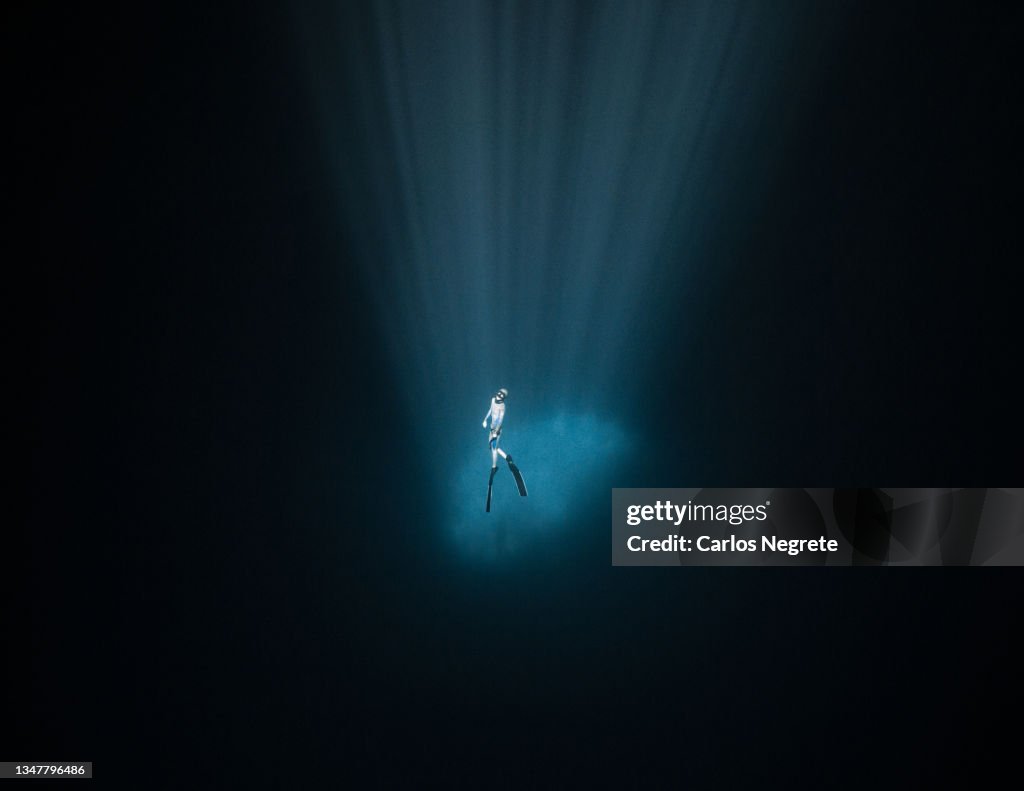 Freediver inside the light of a Cenote at 30 meters deep