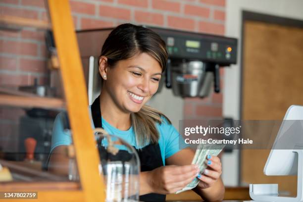 barista counting her tips after working shift at local coffee shop - money advice stock pictures, royalty-free photos & images