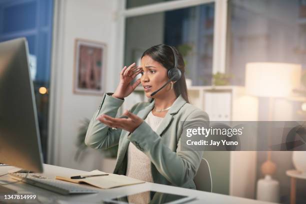 shot of a young woman using a headset and looking stressed in a modern office - crisis hotline stock pictures, royalty-free photos & images