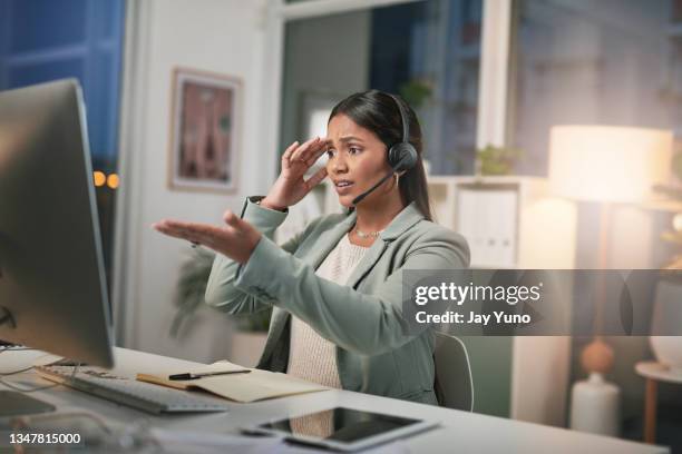 shot of a young woman using a headset and looking stressed in a modern office - crisis hotline stock pictures, royalty-free photos & images