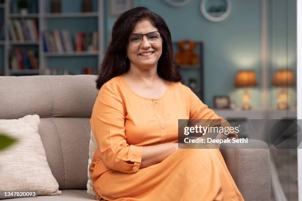 happy senior woman on sofa stock photo - modern india stock pictures, royalty-free photos & images