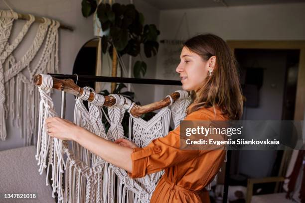 young woman making a macrame work inside her house - orange dress stock pictures, royalty-free photos & images