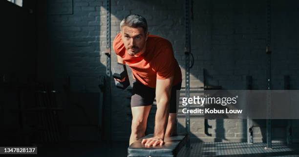 shot of a handsome mature man using dumbbells during his workout in the gym - gym determination stock pictures, royalty-free photos & images