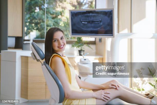 portrait of happy young woman sitting in a dentist’s chair - dentists chair stockfoto's en -beelden