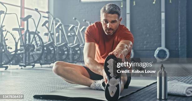 aufnahme eines hübschen reifen mannes, der nach dem training allein im fitnessstudio sitzt und sich dehnt - dehnen stock-fotos und bilder