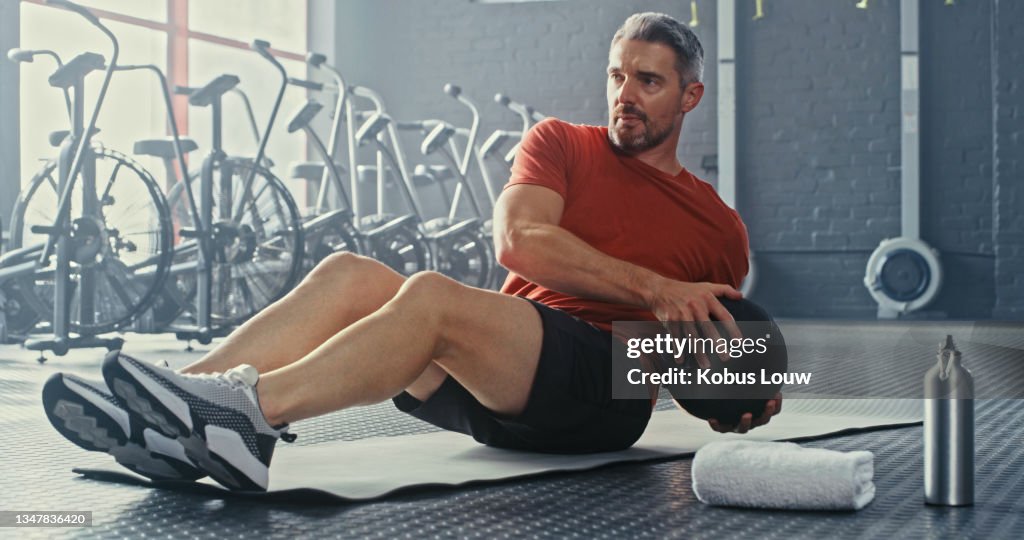 Shot of a handsome mature man using a medicine ball during his workout in the gym