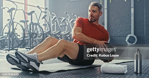 Shot of a handsome mature man using a medicine ball during his workout in the gym Shot of a handsome mature man using a medicine ball during his workout in the gym