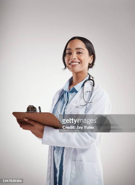 foto de una doctora sosteniendo un portapapeles mientras está de pie sobre un fondo gris - clipboard fotografías e imágenes de stock