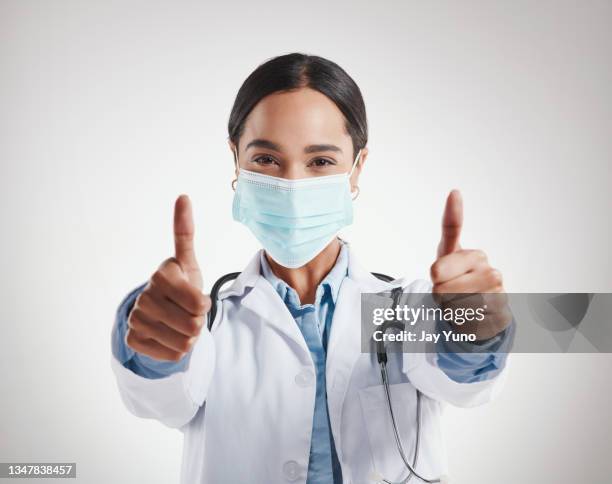studio shot of a female doctor wearing a mask and showing thumbs up - medical thank you imagens e fotografias de stock