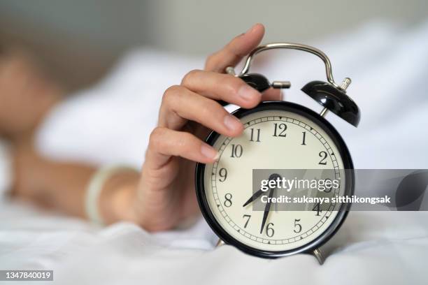 close up hand of woman touching alarm clock at bedroom at home. - wecker stock-fotos und bilder