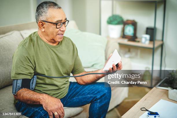 aufnahme eines älteren mannes mit einem blutdruckmessgerät zu hause - blood pressure stock-fotos und bilder