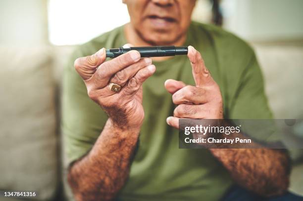 aufnahme eines älteren mannes, der ein fingerstechgerät verwendet, um seinen blutzuckerspiegel zu überprüfen - diabetes pictures stock-fotos und bilder